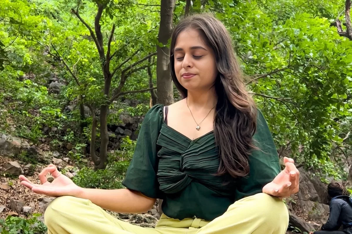 A person sitting in a cross-legged meditation posture outdoors, practicing mindfulness and inner awareness in nature