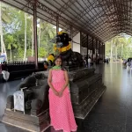 Devotee standing near large Nandi statue in Maheswaram Shiva Temple Kerala