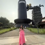 Visitor posing in front of world tallest Shiva Lingam in Kerala