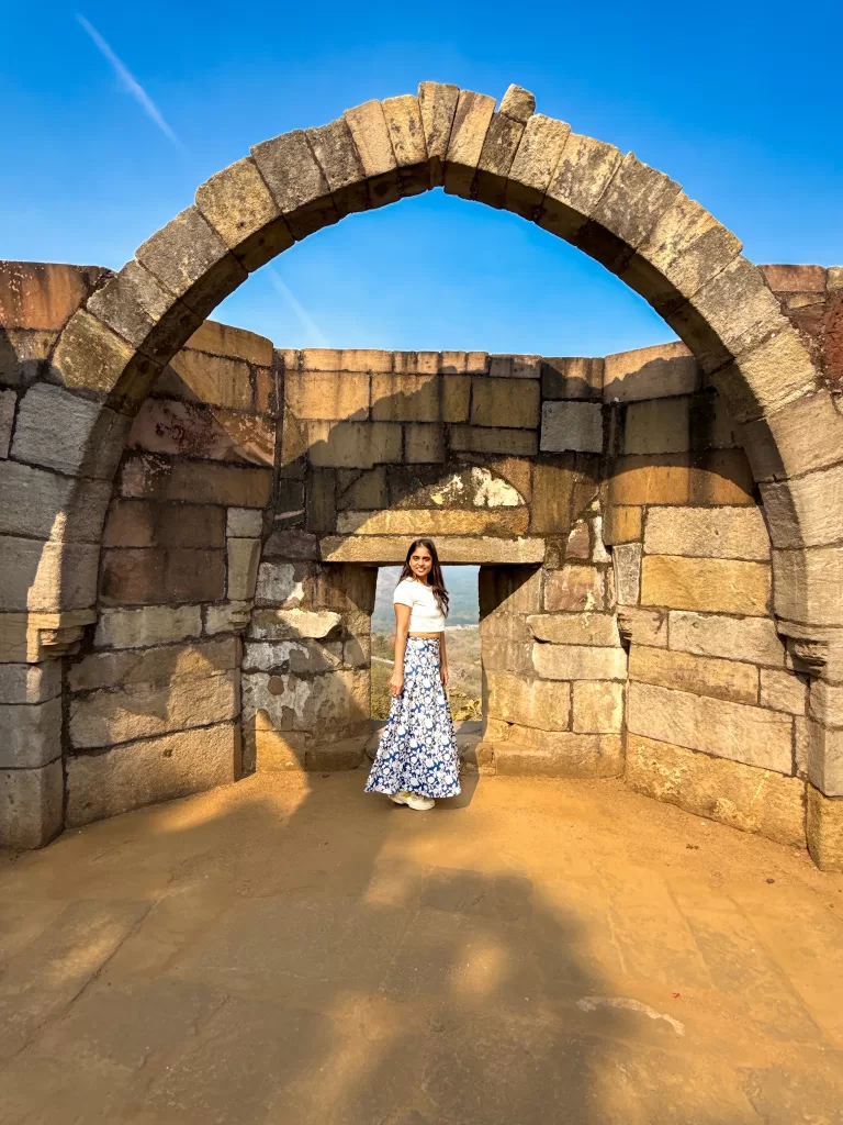 Woman standing under stone arch at Saat Kaman Champaner Gujarat