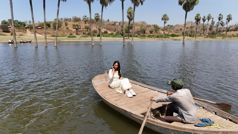 Woman enjoying boating at Moti Bhamri on Karjan River with scenic palm trees and hills near Vadodara
