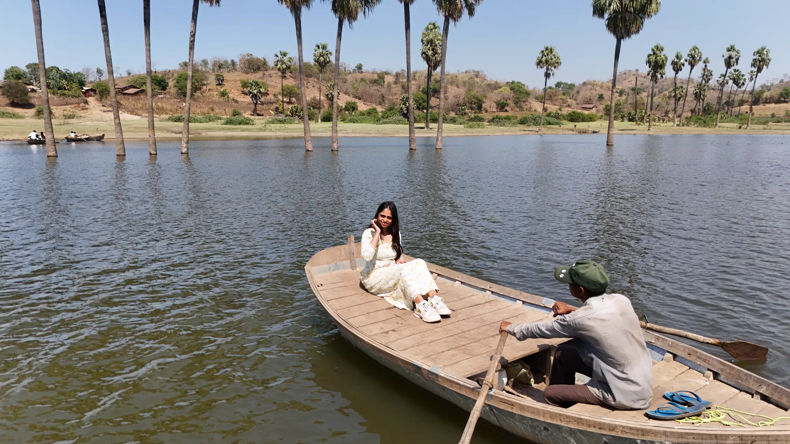 Woman enjoying boating at Moti Bhamri on Karjan River with scenic palm trees and hills near Vadodara